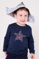 a 5 year old boy wearing a navy long sleeve christmas t-shirt with a festive star on the front made from Liberty Adelajda's Wish star print on the front.