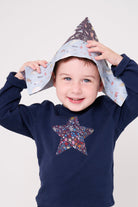 a 5 year old boy wearing a navy long sleeve christmas t-shirt with a festive star on the front made from Liberty Adelajda's Wish star print on the front.