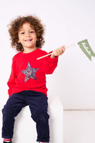 A 3 year old boy wearing a red Christmas t-shirt with a liberty Adelajda's Wish star pritn fabric Christmas star appliquéd on the front. 