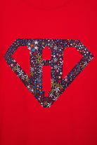 A close up of a red cotton personalised t-shirt with his initial in a superhero emblem Liberty star Adelajda's Wish fabric appliquéd on the front.