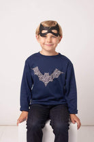 A boy in a  navy cotton tee with a halloween bat on it made from Liberty Alba print fabric.