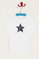 A white bodysuit babygrow with a Liberty Christmas print festive star sewn on the front.