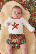 A baby wearing a white bodysuit babygrow with a Liberty My Little Star print festive star sewn on the front.