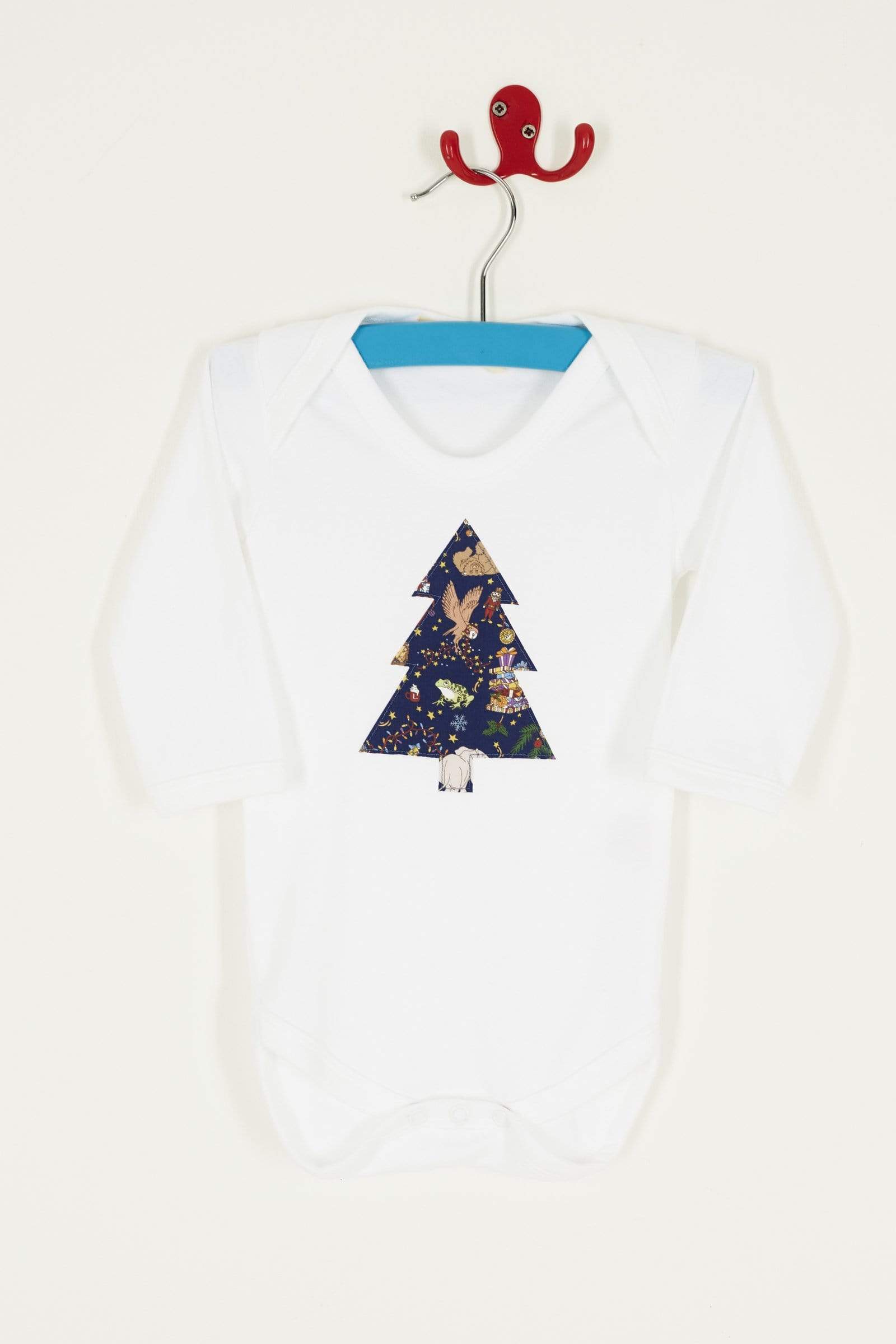 A white bodysuit babygrow with a Liberty Christmas print Christmas tree sewn on the front.