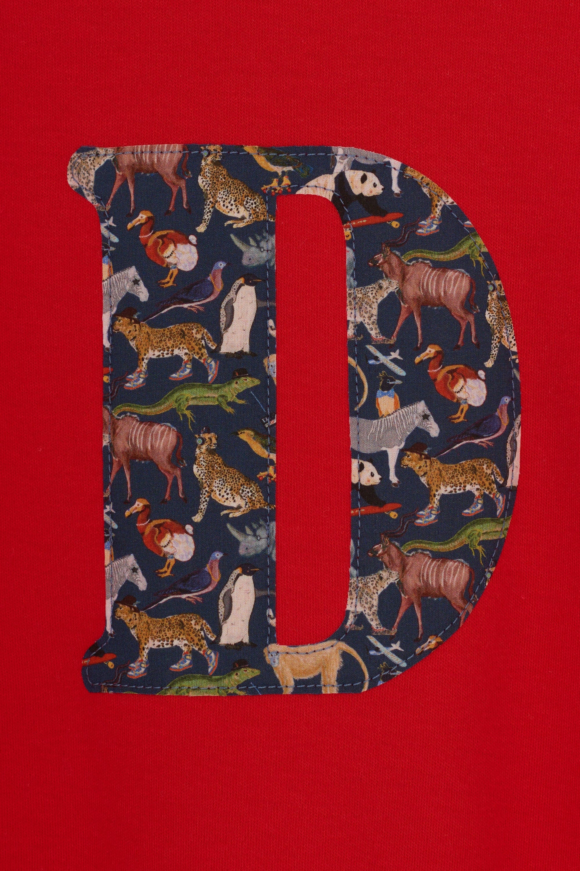 A personalised red cotton t-shirt with his initial on the front made out of a Liberty zoo animal print Quey 2.