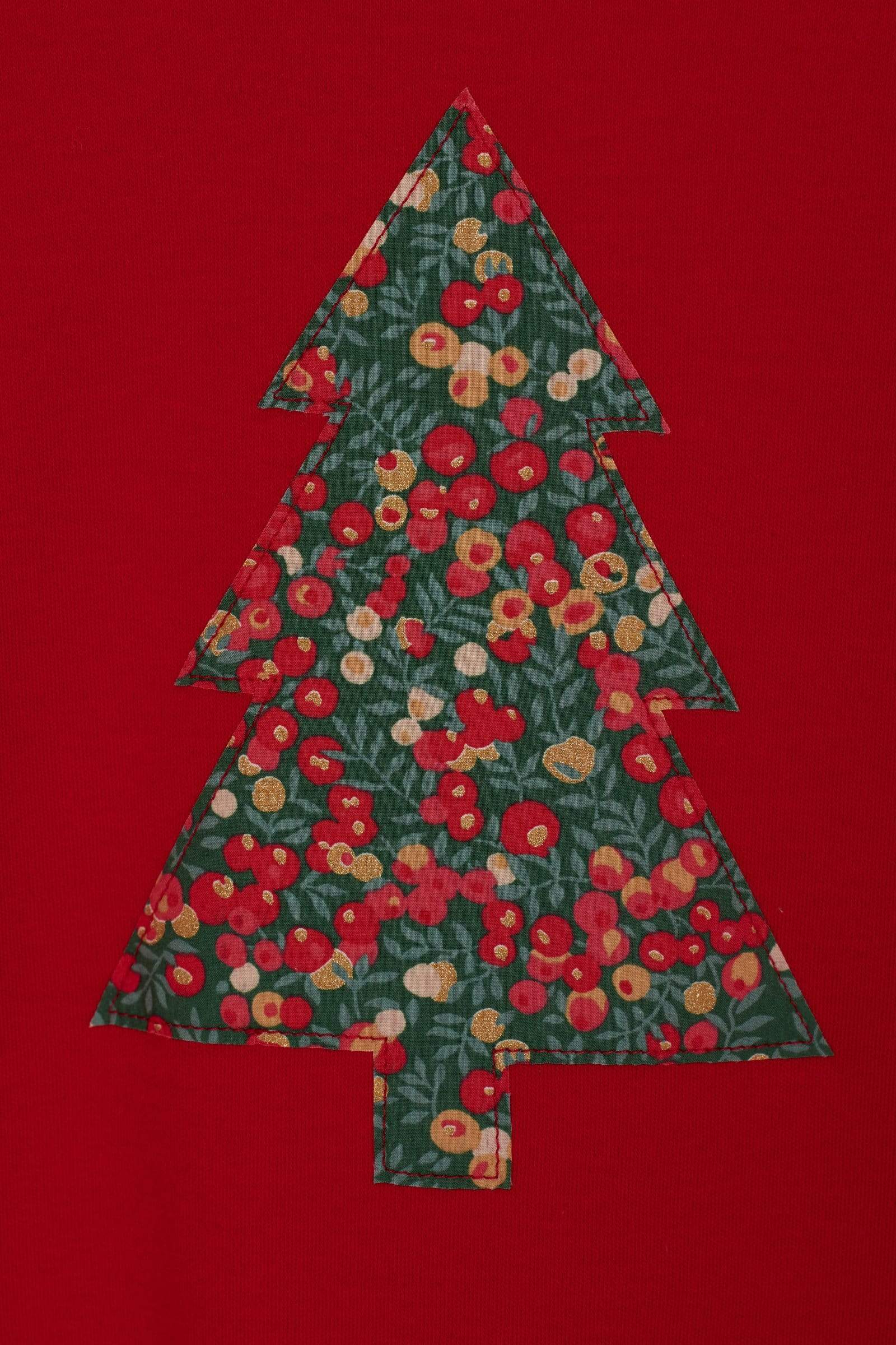 A close up of a festive red t-shirt with a Christmas tree on the front made from Liberty Glitter Wiltshire berry fabric.