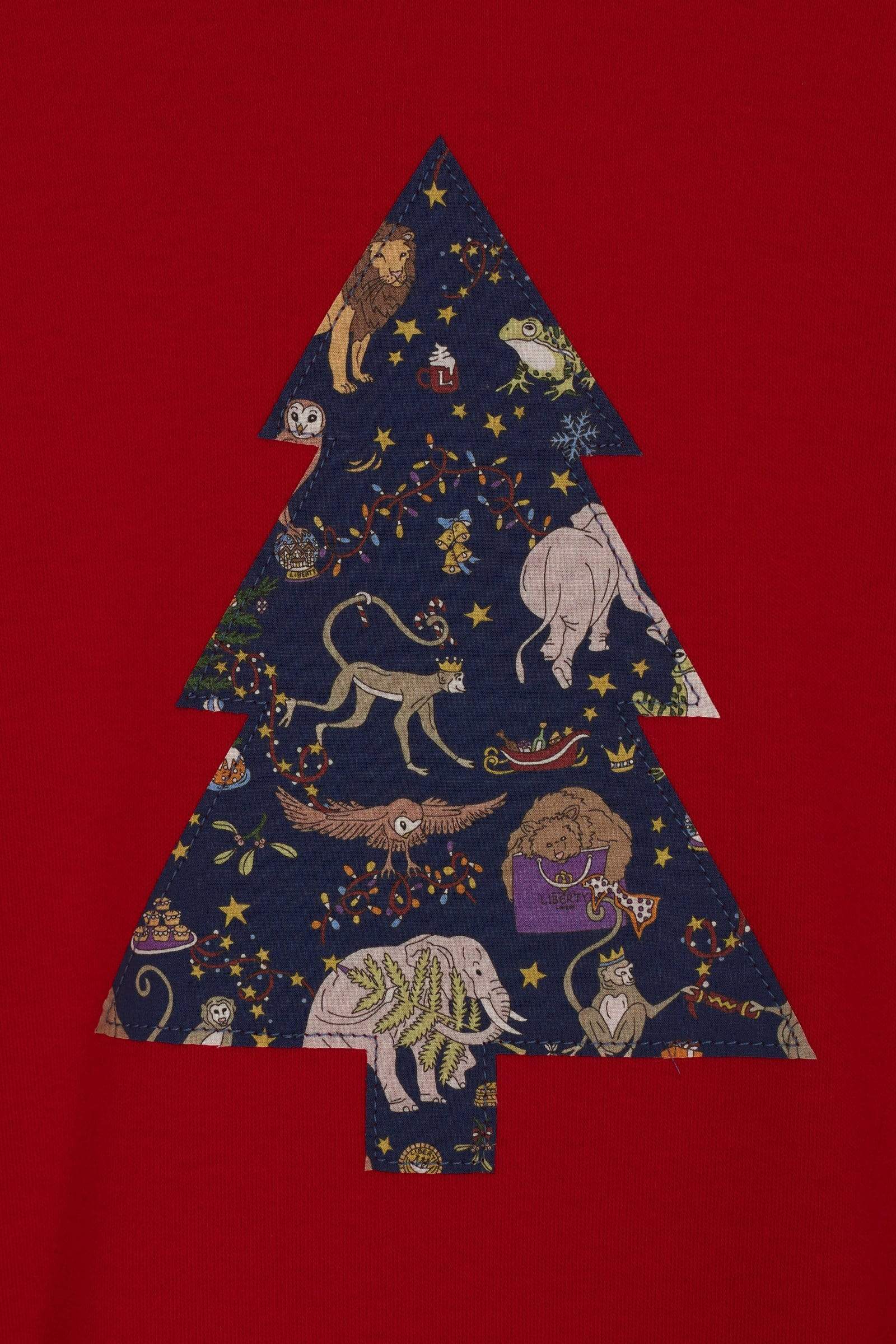 A close up of the appliqué on a festive red t-shirt with a christmas tree on the front made from Liberty Christmas fabric.